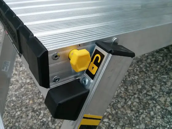 When you extend the legs out on the platform, they LOCK in place so the platform doesn't collapse if you rock back and forth. You press in this yellow button so the legs can be folded back to store the platform. Photo credit: Tim Carter