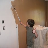 Boy painting wall with long roller