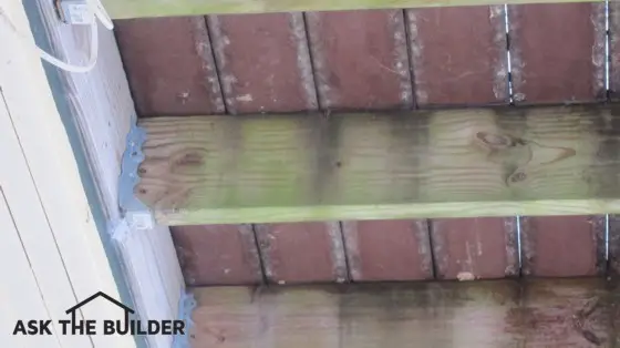 The floor joists under this deck are covered with unsightly mildew and algae. Photo Credit: Tim Carter