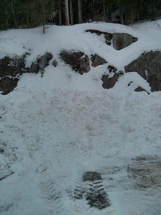 This is snow piled up to make room for MORE as the cul de sac was shrinking in size by the day. The top of the granite ledge is about 18 feet off the pavement. Photo credit: Tim Carter