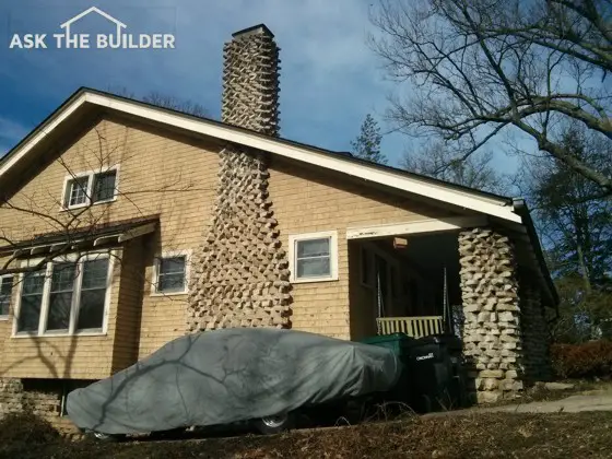 Even from the ground an expert can see this stone chimney doesn’t have the right cap on it. Don’t be fooled by the metal hood. Photo credit: Tim Carter