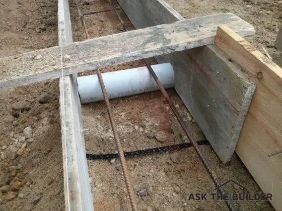 All that’s missing is the concrete for this foundation footing. The white pipe allows water to pass from under the house to the low spot on the lot. Photo Credit: Tim Carter