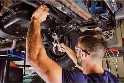 mechanic working on underside of car