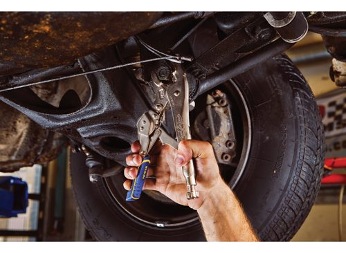 vise grips working on underside of a car