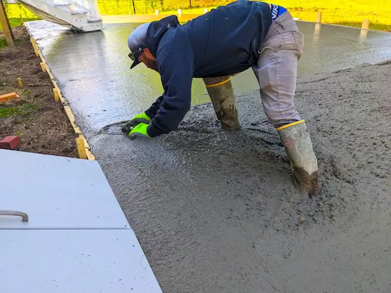 fresh concrete slab being troweled by a worker