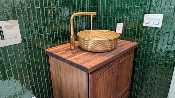 brass vessel sink green vertical subway tile walnut vanity